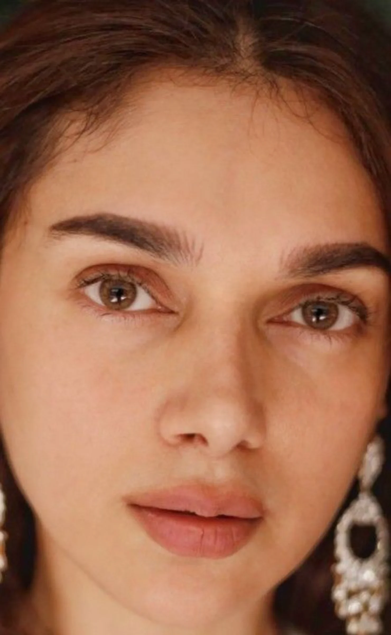 Close-up portrait of Aditi Rao Hydari, an Indian actress, with light brown eyes, dark eyebrows, and a large ornate dangling earring on her right ear.