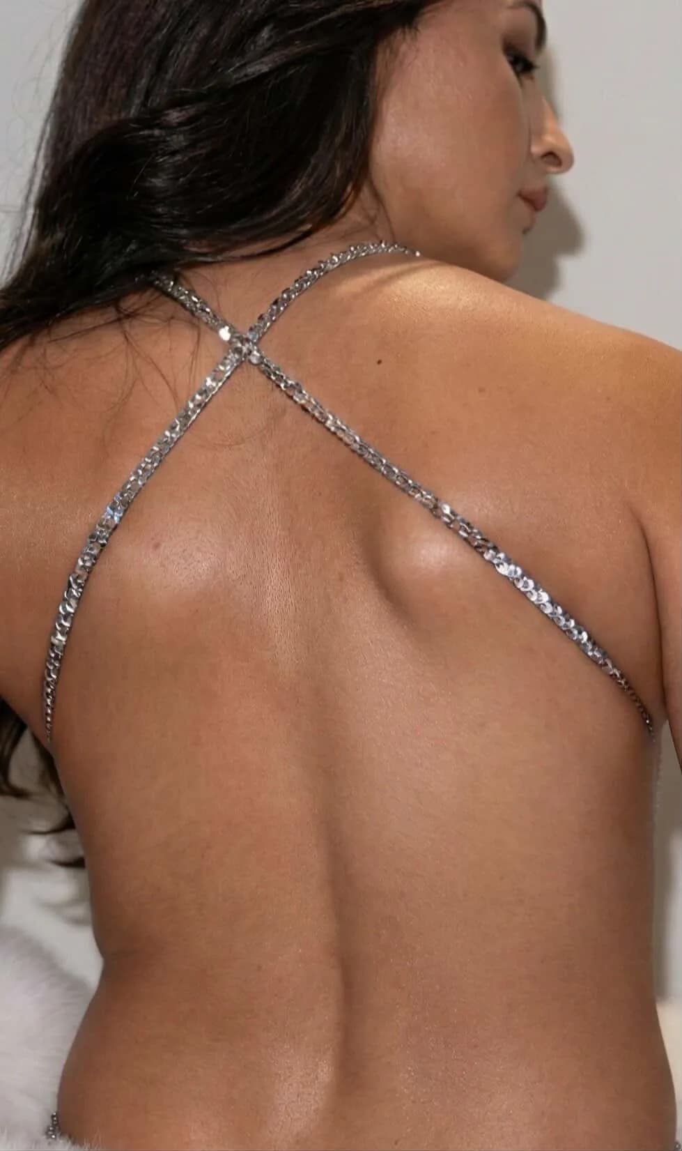 Alia Bhatt posing in a silver sequined backless top showing side profile