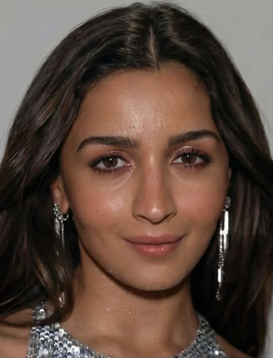 Close-up facial portrait of Alia Bhatt wearing silver statement earrings and silver sequin attire