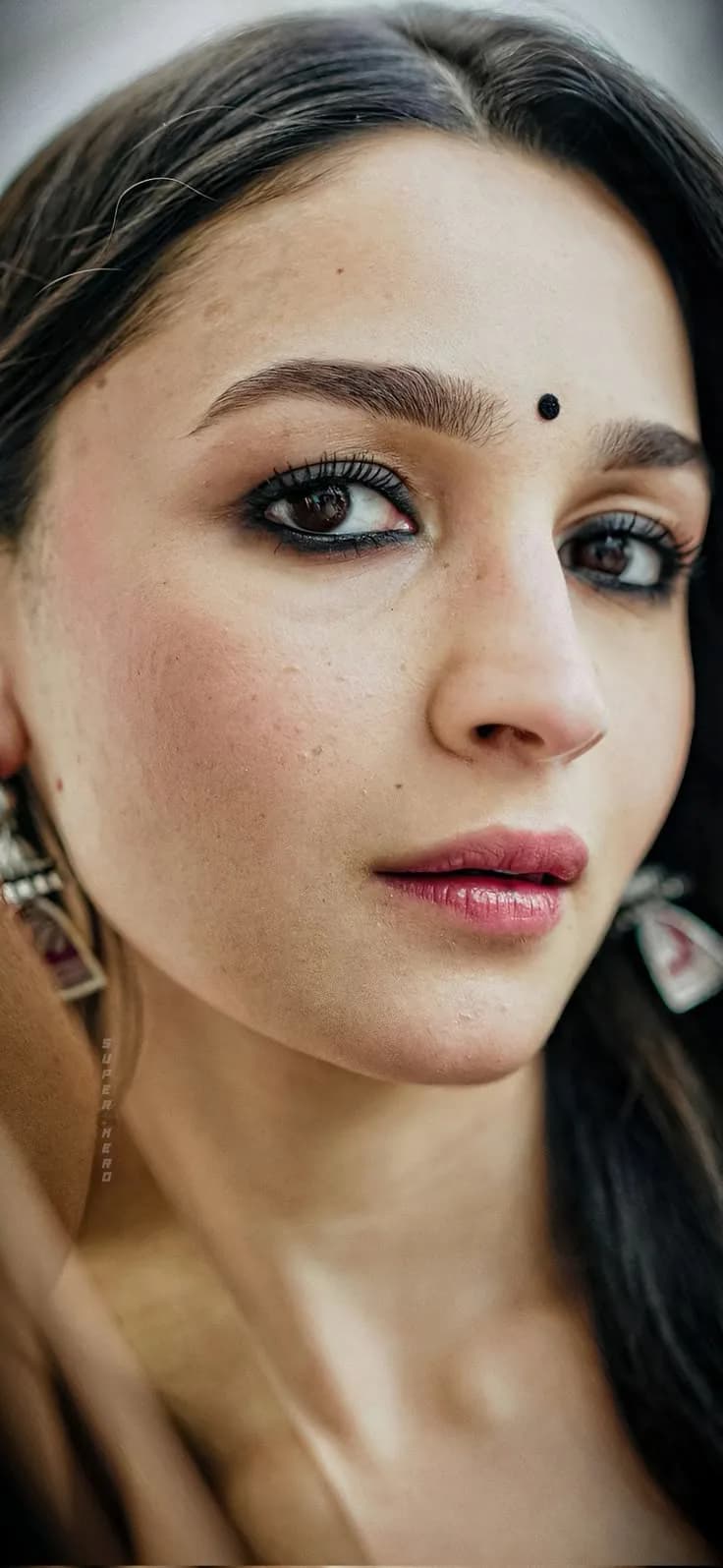 Extreme close-up facial portrait of Alia Bhatt wearing a small black bindi and dark kohl eyeliner.