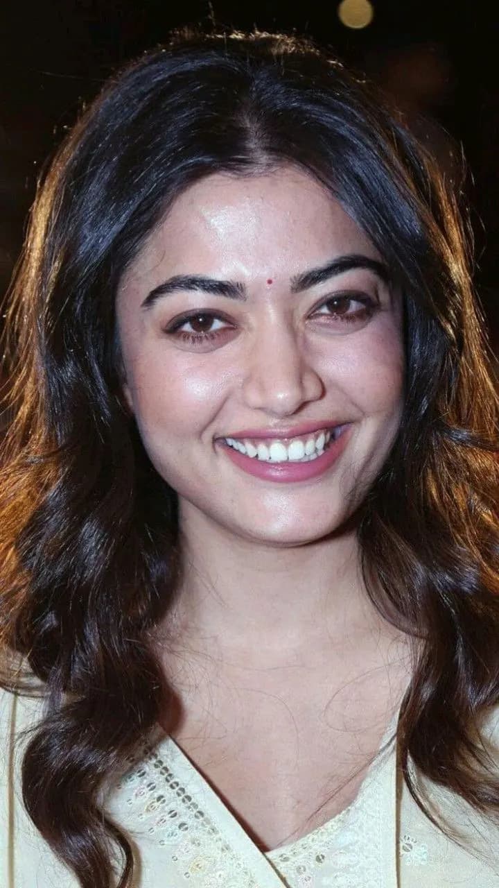 Close-up portrait of Rashmika Mandanna smiling in a cream traditional outfit with a bindi.