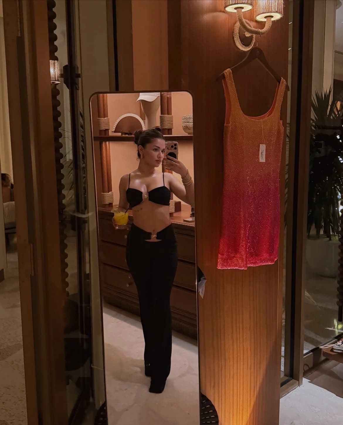 Avneet Kaur taking a mirror selfie in a black bralette crop top and low-rise trousers.