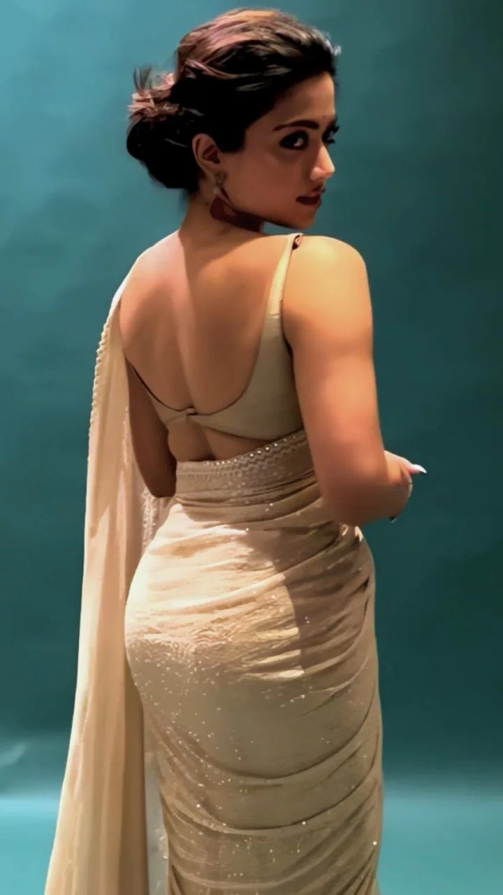 Rashmika Mandanna posing in a beige backless saree looking over her shoulder